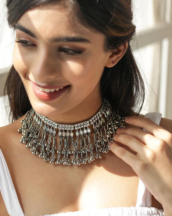 A woman wearing a silver oxidised bell-like choker necklace with a mirrored design.