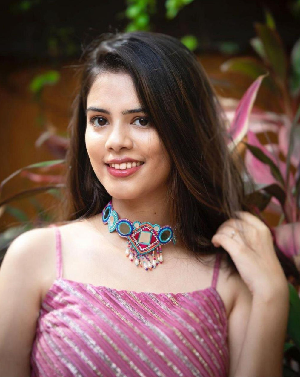 model wearing a multicolor beaded choker necklace with geometric patterns and mirror accents.