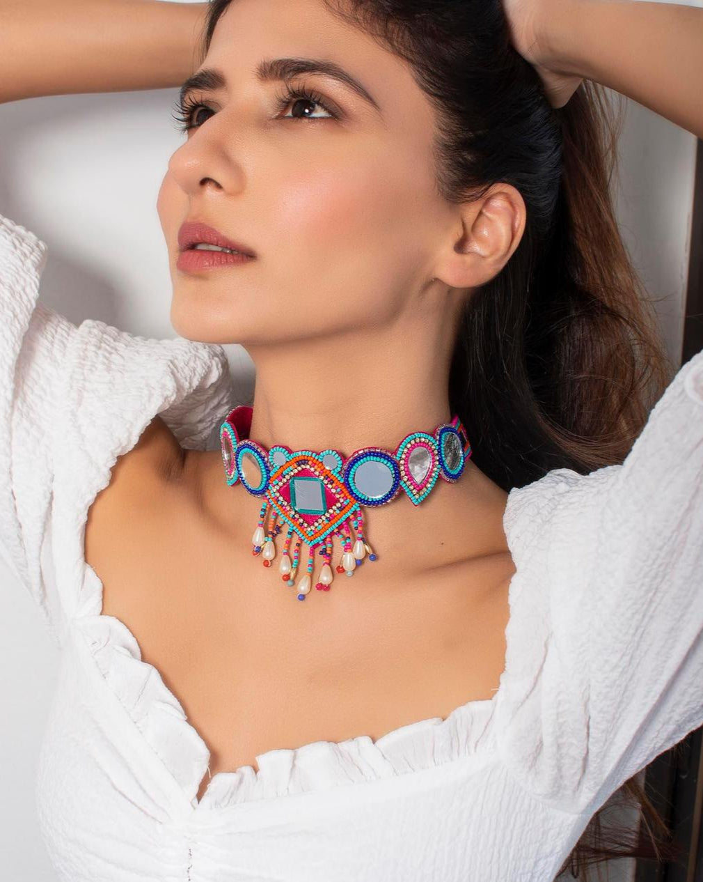 model wearing multicolour beaded choker necklace with geometric patterns and mirror accents.