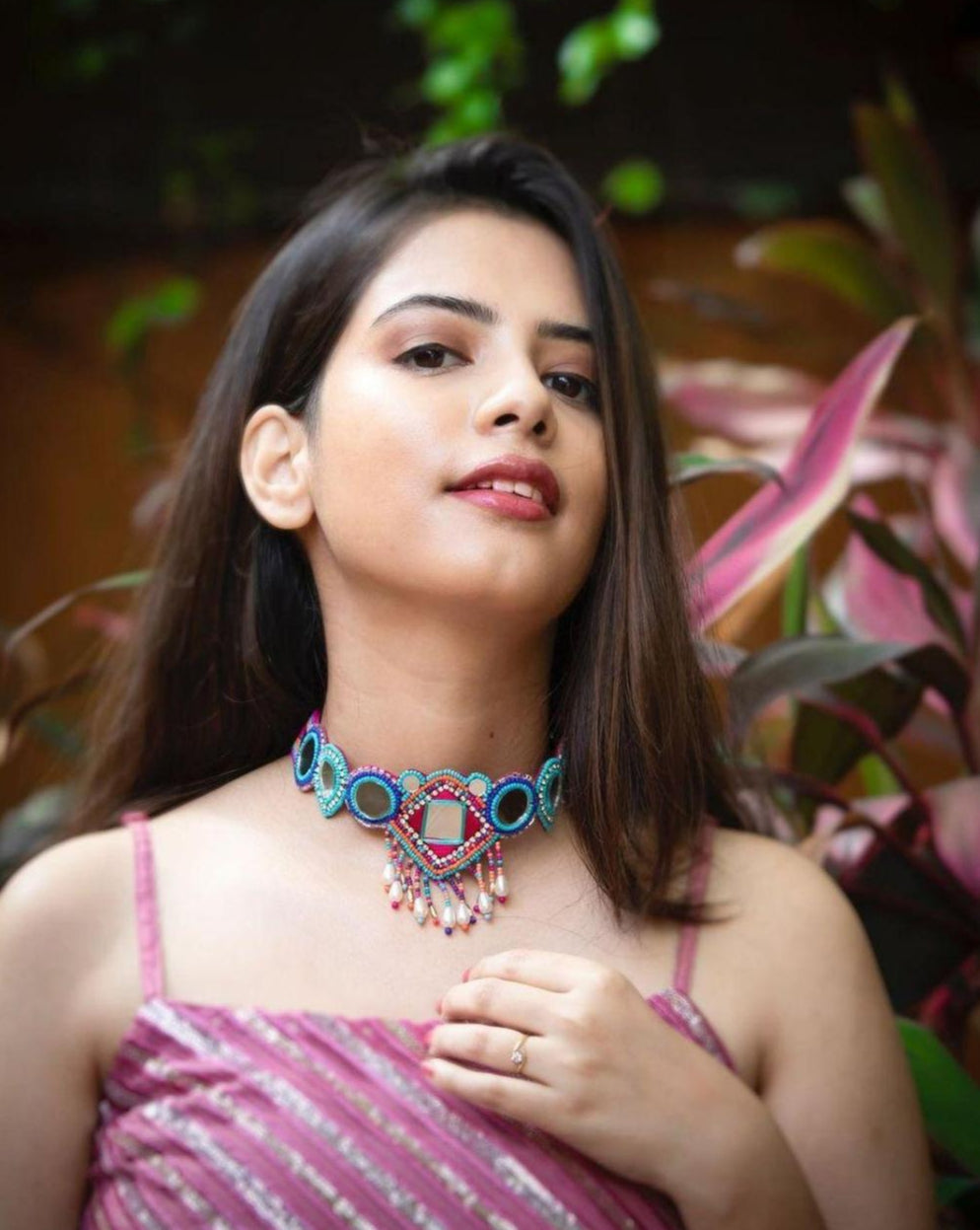 model wearing multicolor beaded choker necklace with geometric patterns and mirror accents.