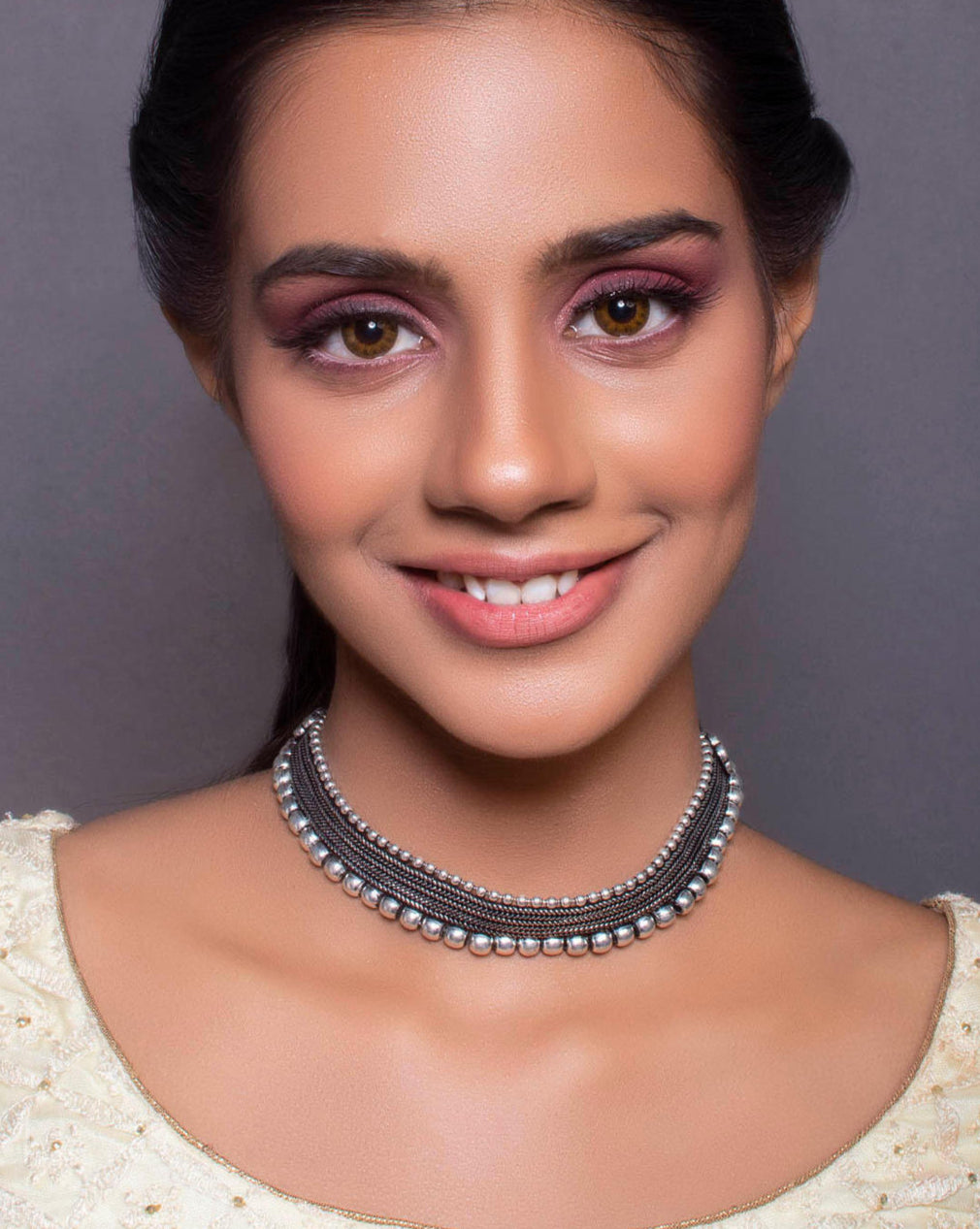 A woman wearing a silver oxidised metal choker necklace with black thread.