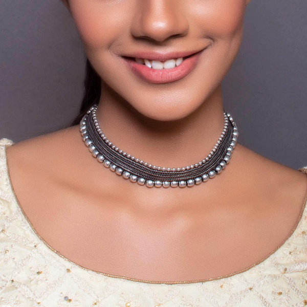 A woman wearing a silver oxidised metal choker necklace with black thread.