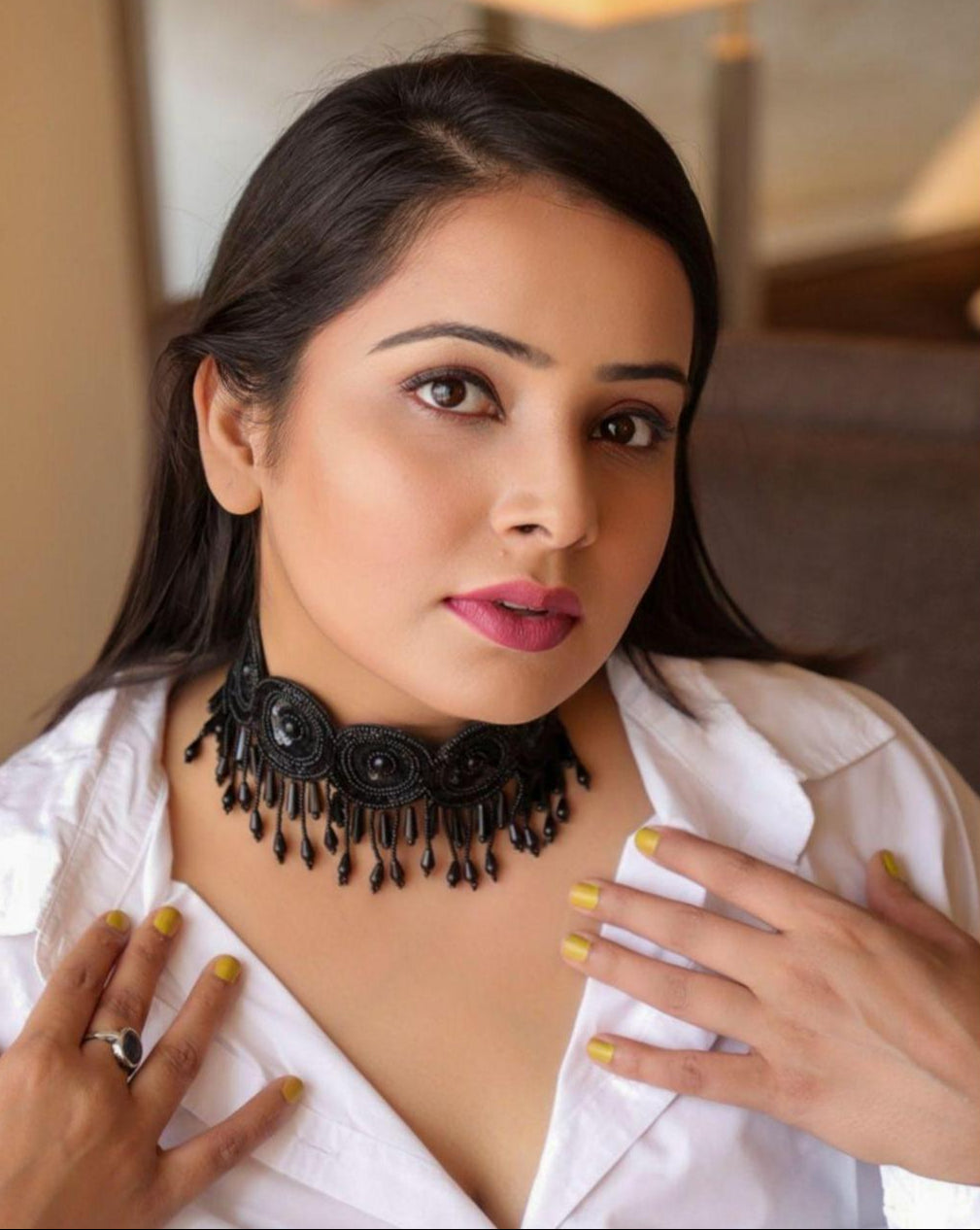 model wearing black seed bead choker necklace with floral motifs and pearl accents.