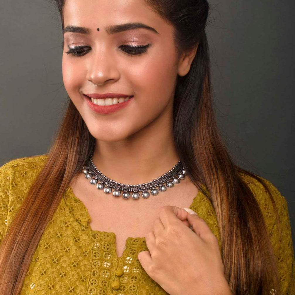 A woman wearing green traditional attire and fida's silver choker necklace with a chain design.