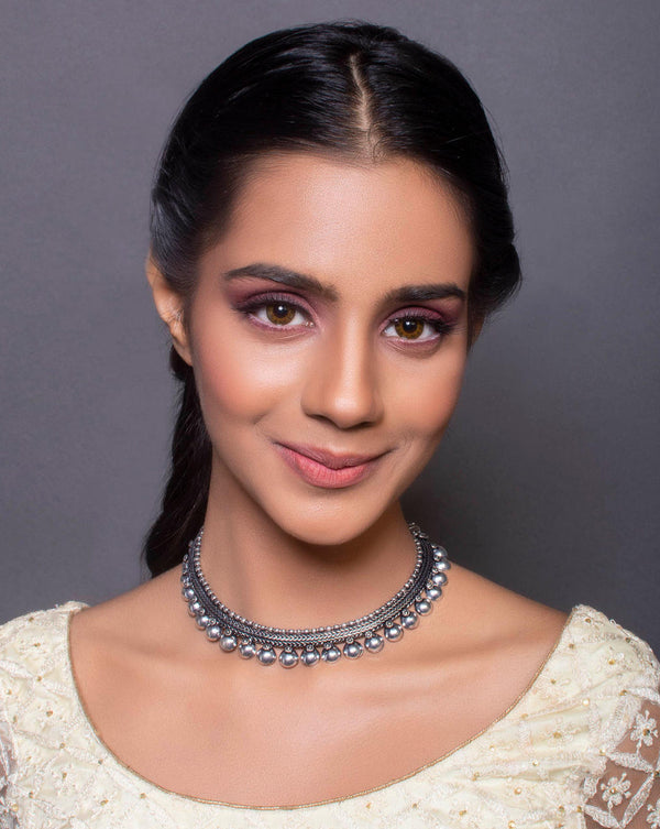 A woman wearing fida's silver choker necklace with a chain design.