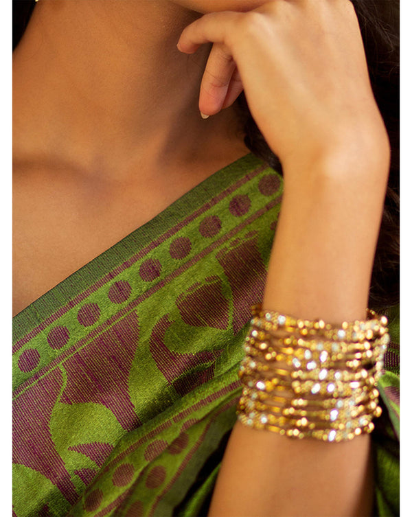 Model Wearing Set of 12 gold-plated metal bangles with sparkling stones and beads. Perfect ethnic jewellery for weddings, parties & traditional celebrations.