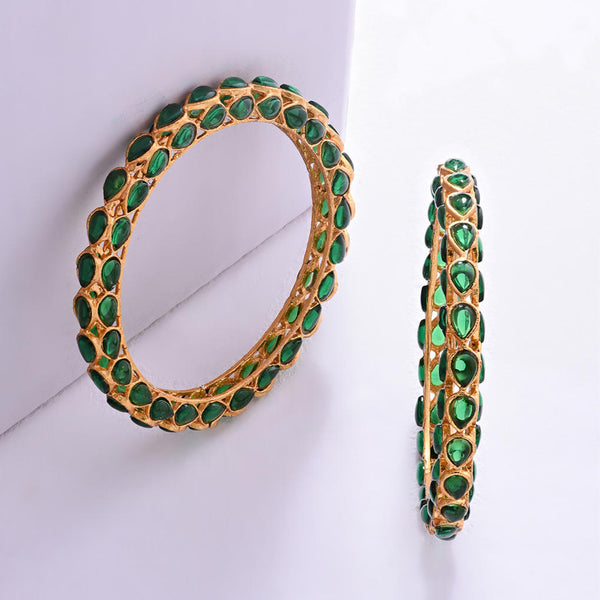 A set of two gold-plated bangles adorned with emerald stones and kundan work, displayed against a white background.