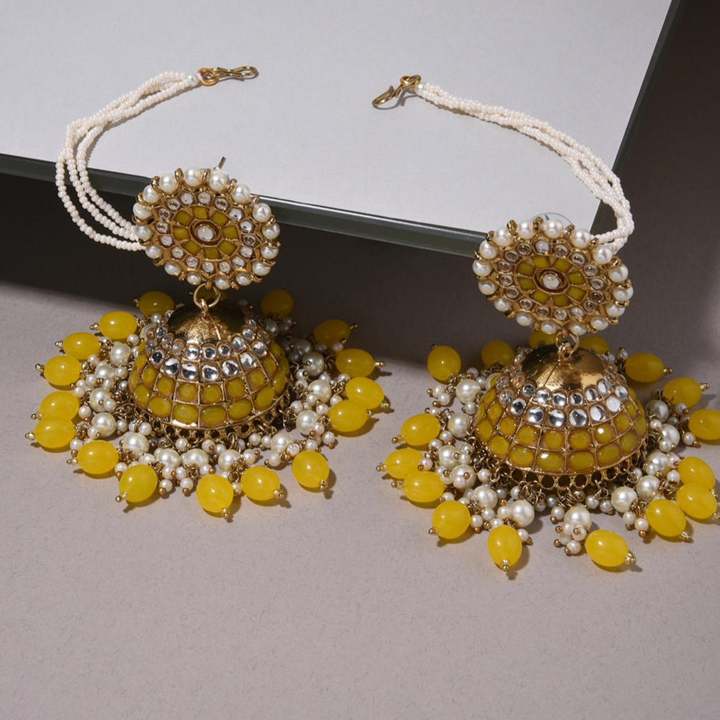 A pair of yellow drop earrings with gold plating and embellishments, featuring artificial beads and stone decorations.