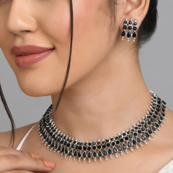 A woman wearing a traditional silver choker necklace with black beads and matching earrings.