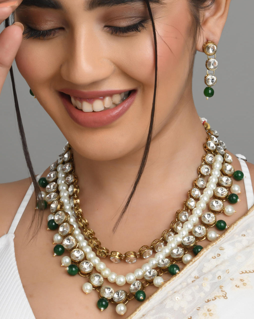 a gold plated necklace with green pearl beaded layers and matching earrings.
