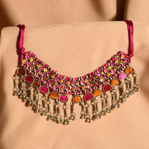 A pink and silver choker necklace with oxidised silver work and vibrant stone inlay, displayed against a beige background.