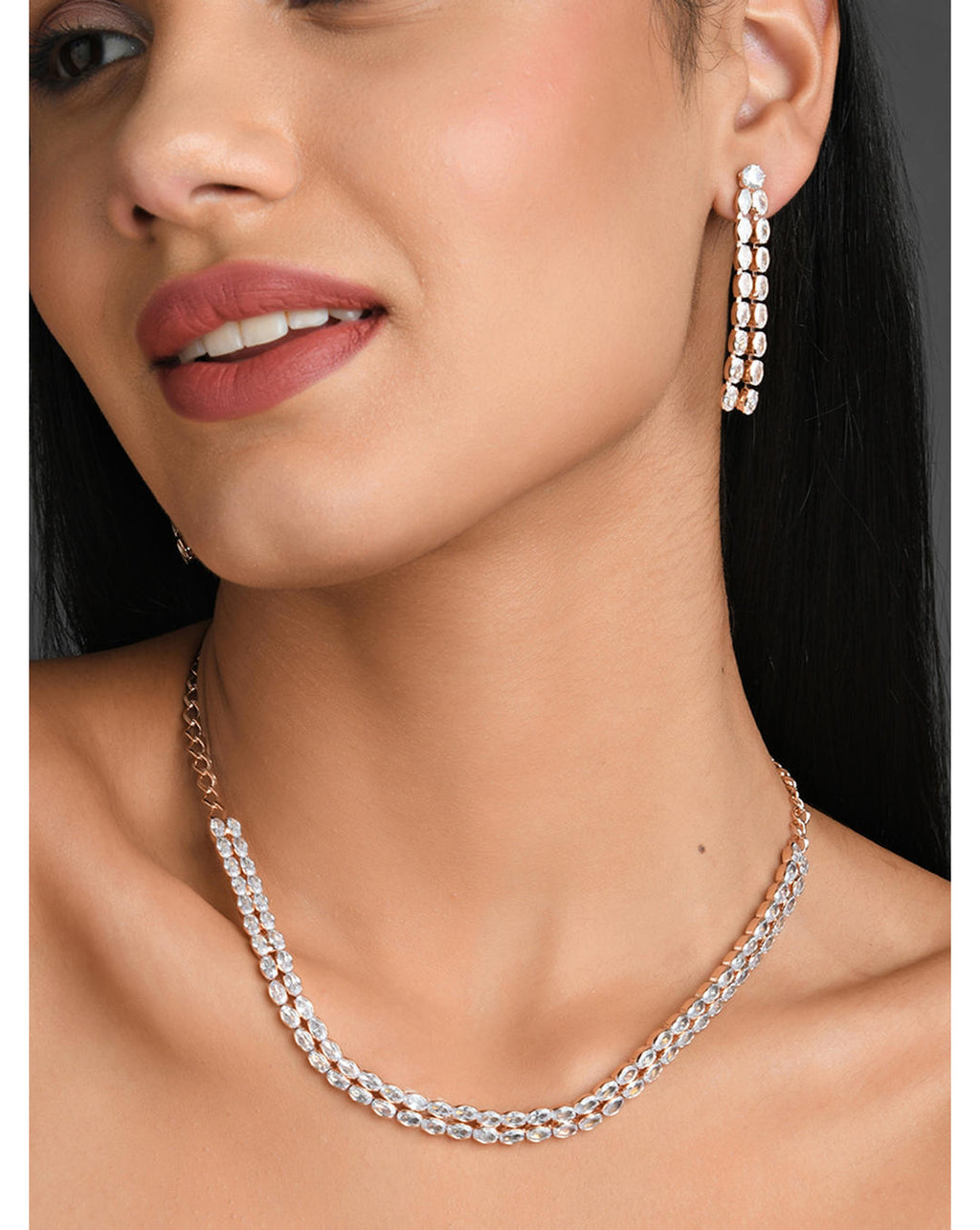 A model wearing a rose gold plated double layered jewellery set with a necklace and earrings.