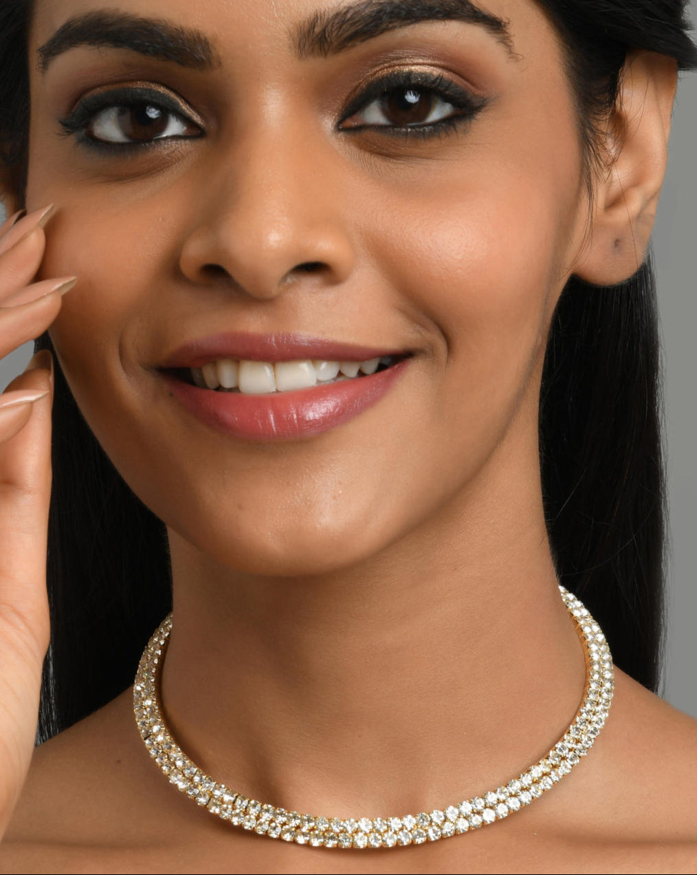 A woman wearing a gold-toned choker necklace adorned with cubic zirconia stones.