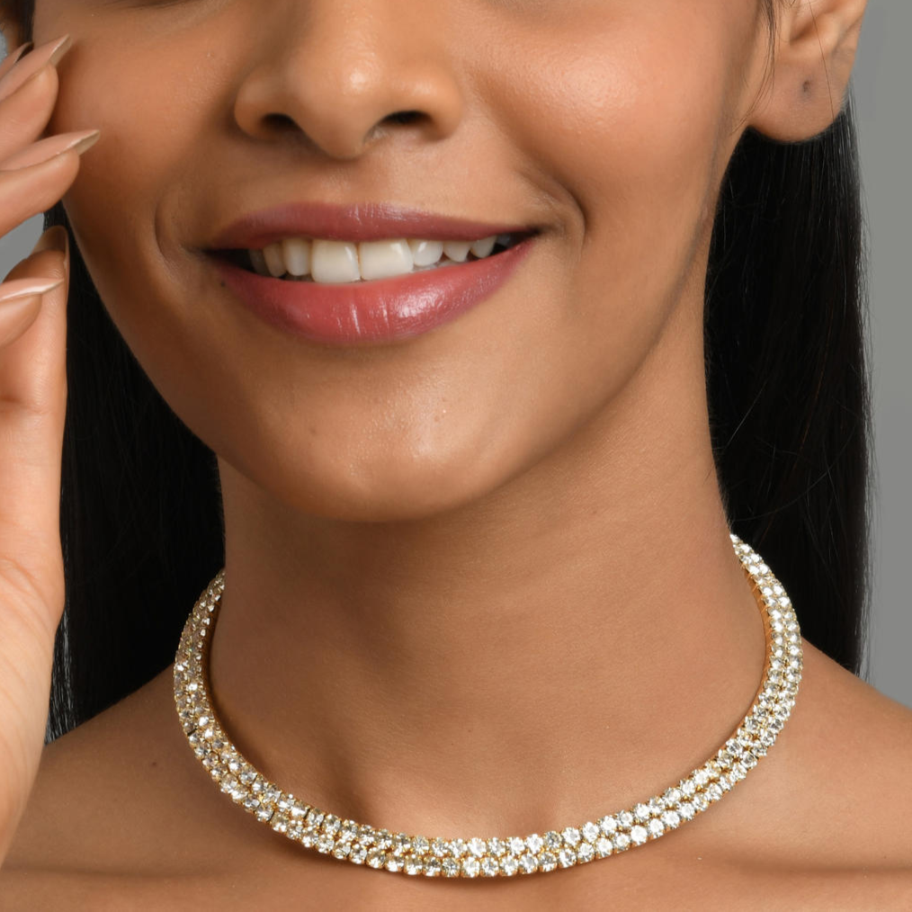 A woman wearing a gold-toned choker necklace adorned with cubic zirconia stones.