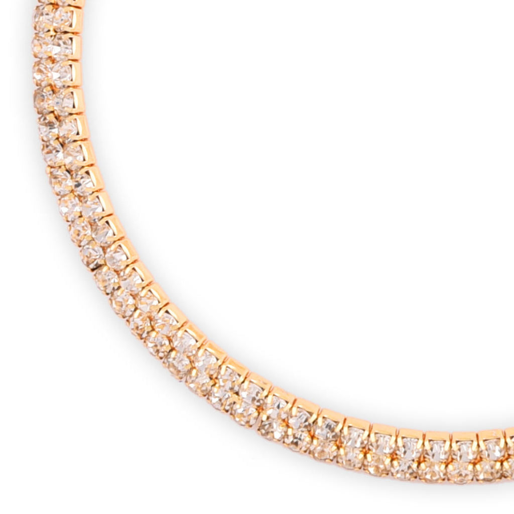 A woman wearing a gold-toned choker necklace adorned with cubic zirconia stones close-up