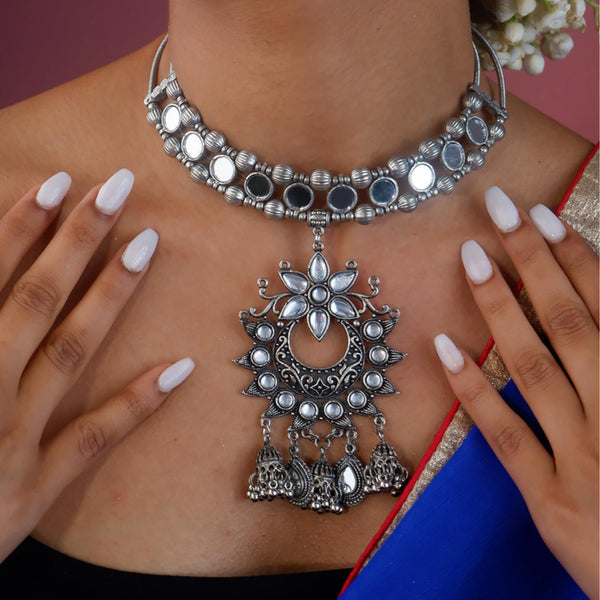 A person wearing a Kundan sparkle choker necklace with intricate mirror work and a large pendant adorned with Kundan stones, along with ghungroo drops.