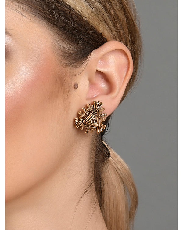A woman's ear wearing a gold plated geometric stud earring.