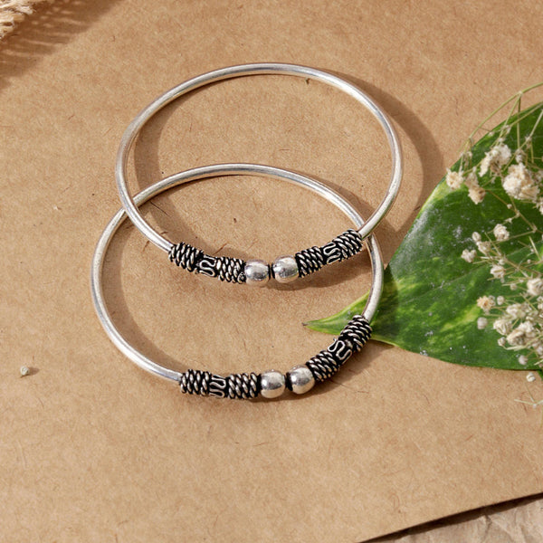 A silver-plated oxidised bangle set, featuring intricate detailing and a textured look.