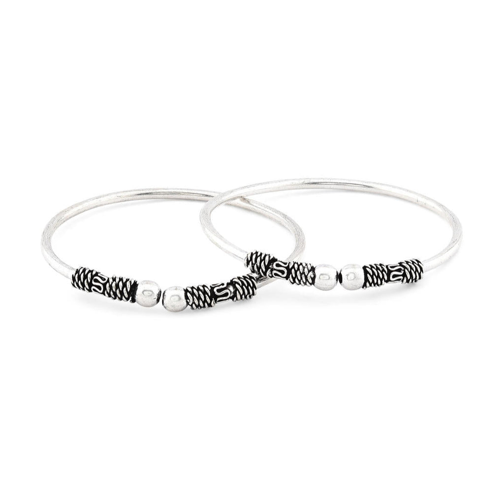 A silver-plated oxidised bangle set, featuring intricate detailing and a textured look with white background.