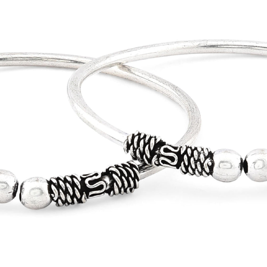 A silver-plated oxidised bangle set, featuring intricate detailing and a textured look close-up.
