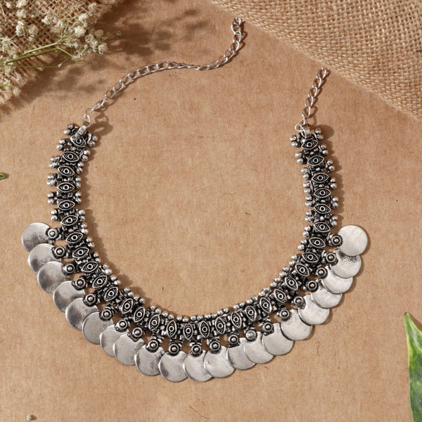 A silver-colored vintage coins choker necklace displayed on a cardboard background with a floral pattern.