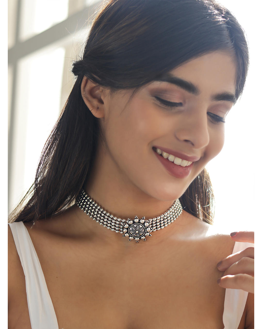 Model wearing A silver oxidised choker necklace with a circular mandala-inspired pendant at the center, suspended from a black thread chain.
