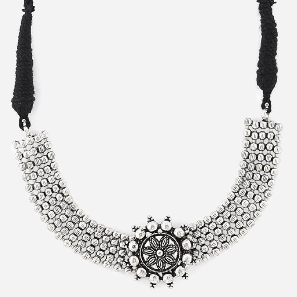 A silver oxidised choker necklace with a circular mandala-inspired pendant at the center, suspended from a black thread chain close-up