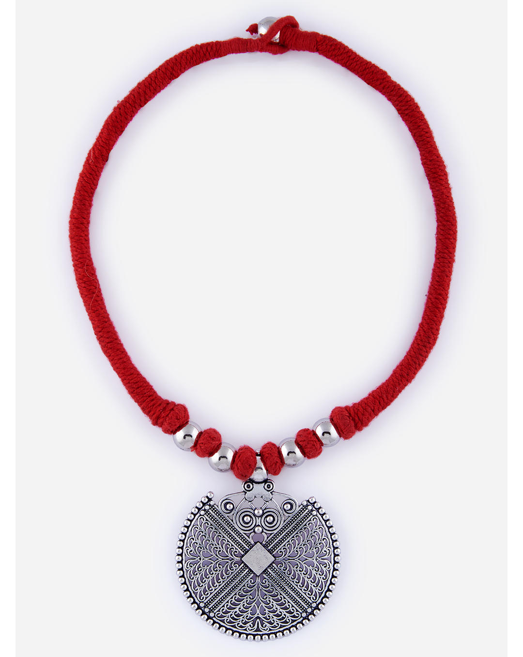 An oxidised mandala pendant necklace with intricate detailing, attached to a red thread with silver beads on white background