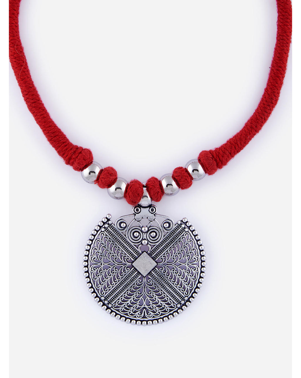 An oxidised mandala pendant necklace with intricate detailing, attached to a red thread with silver beads on close-up on white background