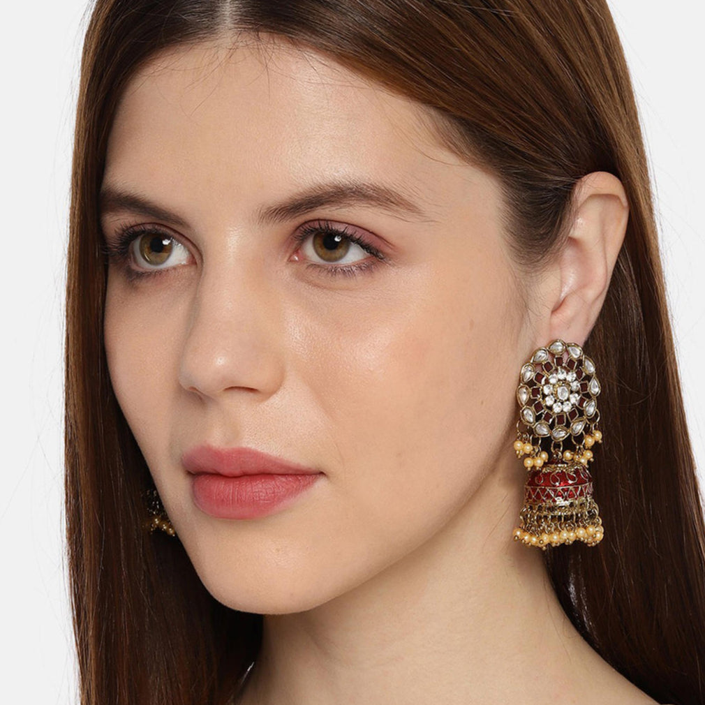 A woman wearing a gold-plated, maroon enamelled kundan bead jhumka earring.