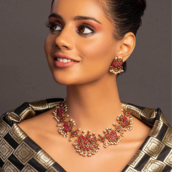 Gold-plated fuchsia stone and pearl choker necklace with matching earrings featuring traditional motifs and drawstring closure – ethnic bridal jewellery set