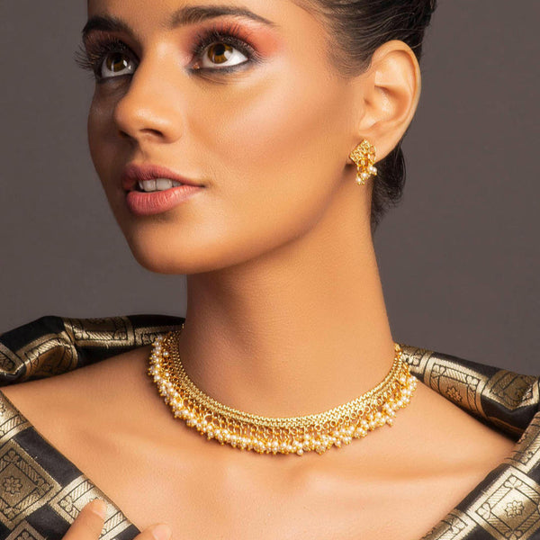 A model wearing a gold-plated necklace with white beads, along with matching earrings, showcasing a piece of temple jewellery.