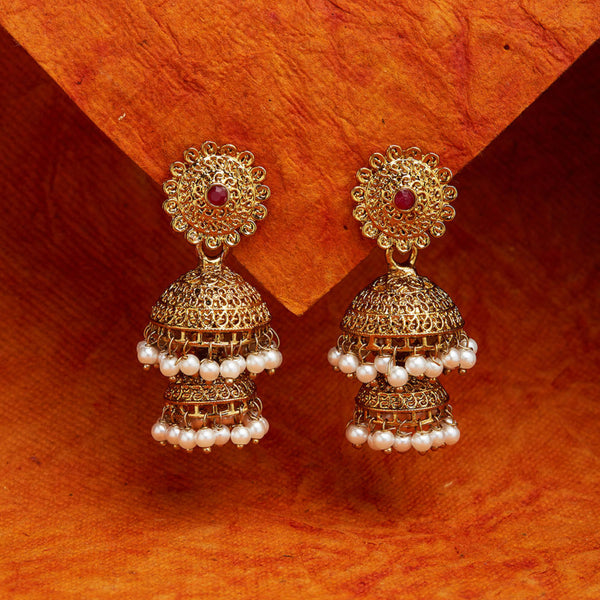 A pair of gold-plated, pearl embellished jhumka earrings displayed on a orange background.