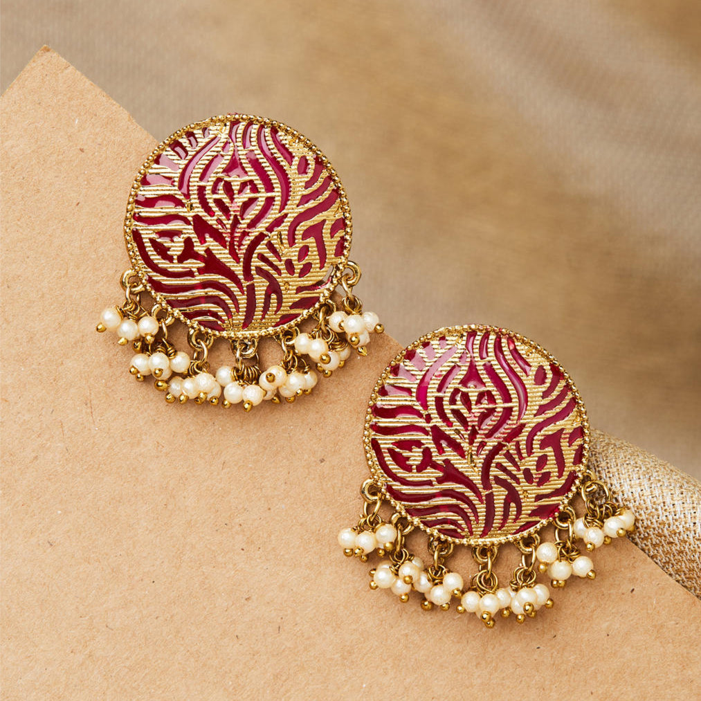A pair of gold-plated spherical stud earrings with pink enamel texture and white bead embellishments, displayed against a beige background.