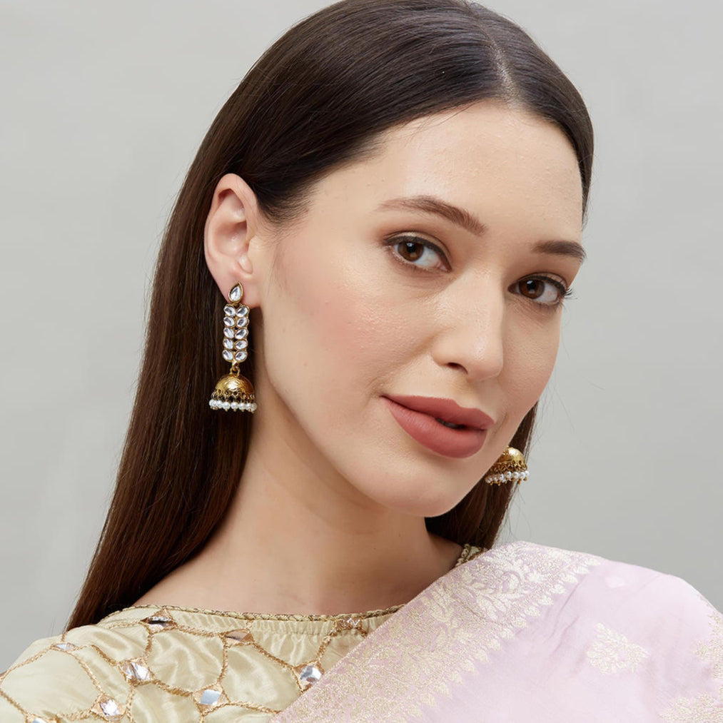 Gold plated jhumka earrings with kundan stone embellishments and a leaf design