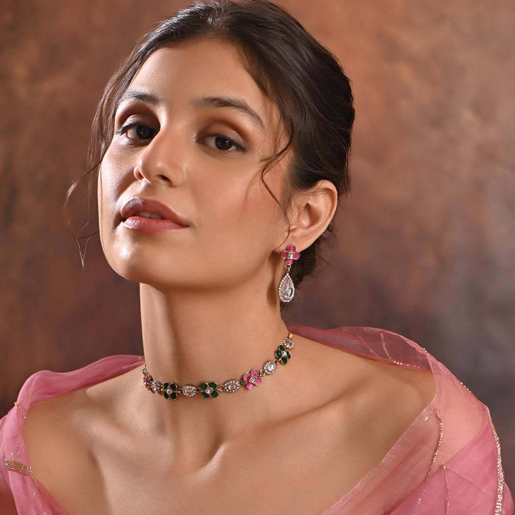 A woman wearing a multicolored traditional jewelry set which includes a floral design necklace and matching earrings.