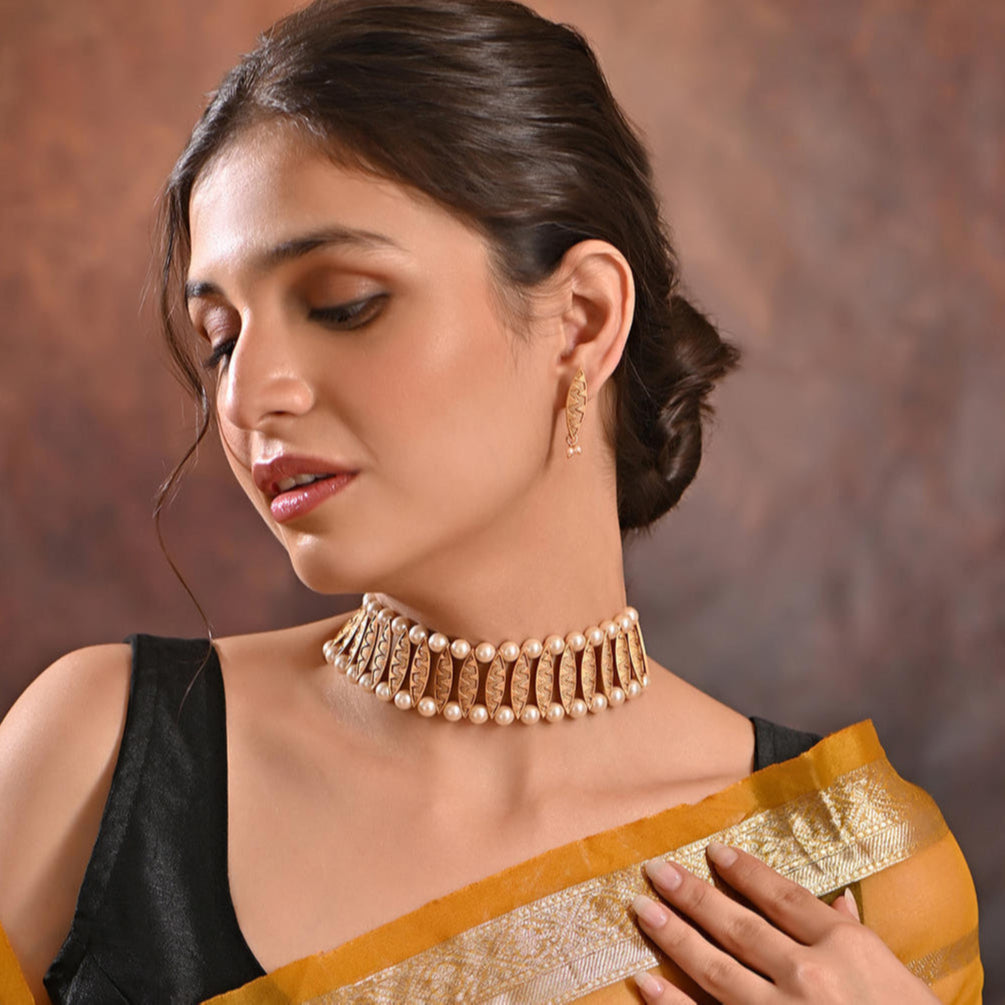 a gold-plated pearl choker necklace and matching earrings from the Fida brand. The jewelry features intricate gold detailing and lustrous pearls.