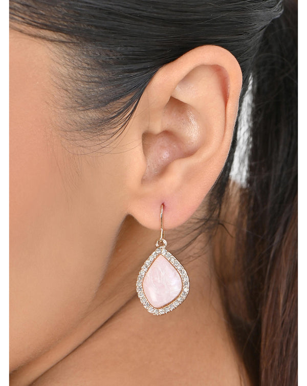 A woman's ear wearing a gold plated asymmetric pink stone drop earring with CZ accents.