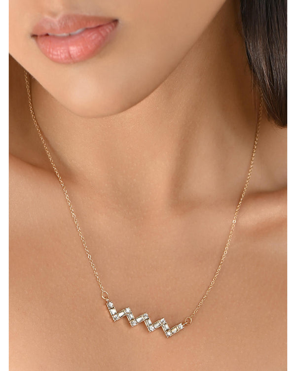 A woman wearing a gold-plated zigzag pendant charm necklace from Toniq.