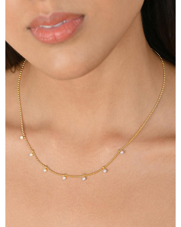 A woman wearing a gold-plated choker necklace with a delicate design.