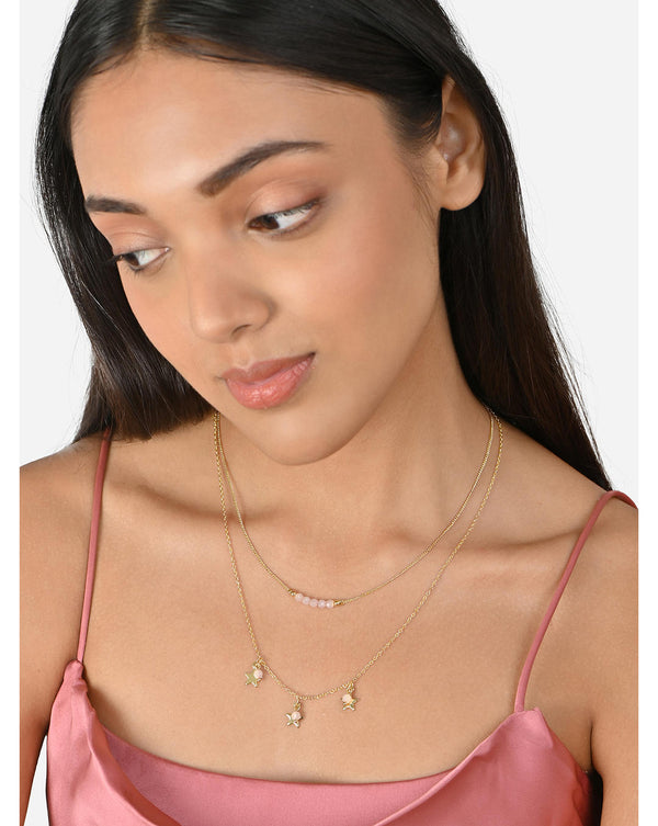 A two-layered gold-plated necklace with star charms on the lower layer and pink beads on the upper layer