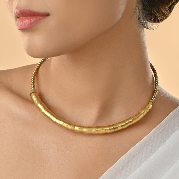 A person wearing a gold-toned choker necklace with a curved rod design covered in fused beads.
