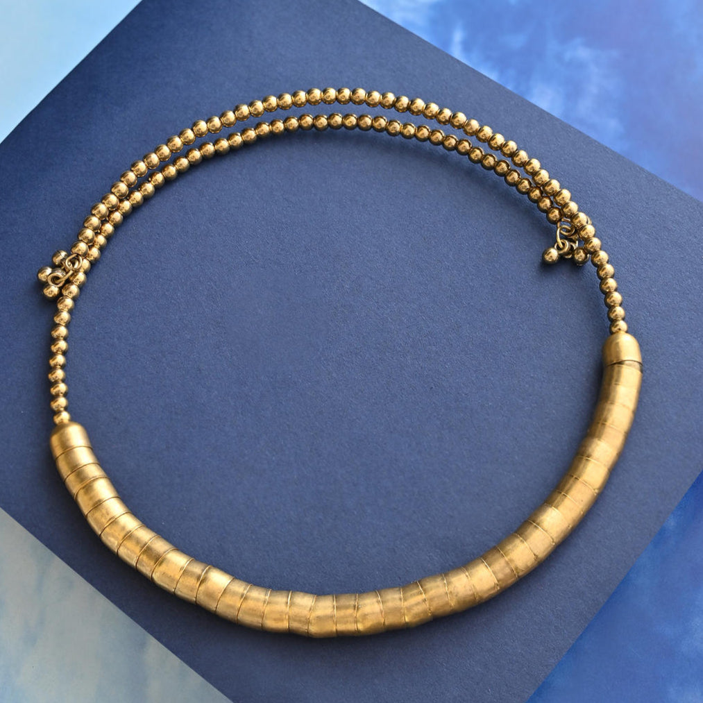 gold-toned choker necklace with a curved rod design covered in fused beads.
