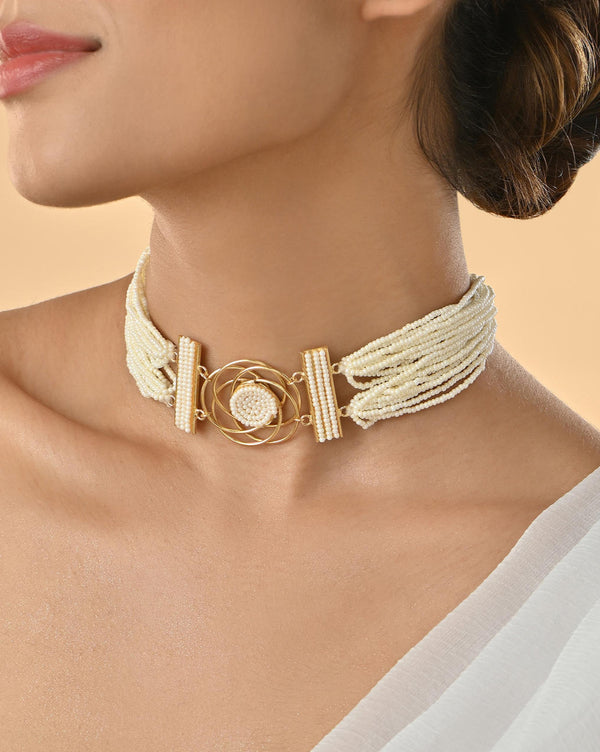 A woman wearing a white pearl and gold-plated multi-strands choker necklace with floral brass accents.