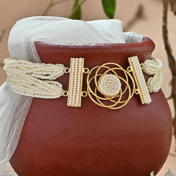 A floral pearl filament choker necklace with gold-toned settings and white pearl floral motifs, displayed on a red base with a white fabric attached to it.