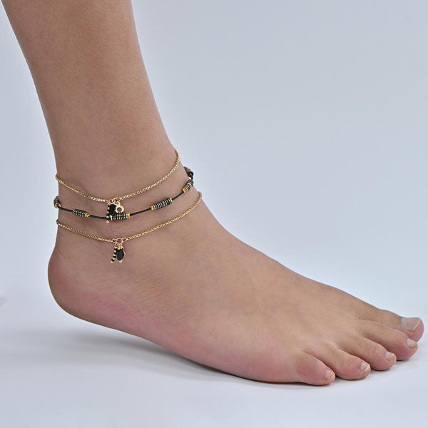 A gold-plated anklet set with black beads, displayed on a person's ankle. ToniQ jewellery is skin safe, nickel free, cadmium free, hypoallergenic, and lab tested for your comfort and trust.