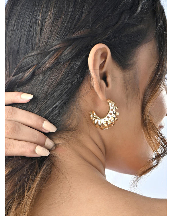 A person viewed from the back wearing gold-toned ribbed hoop stud earrings.