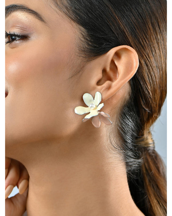 A woman wearing white and beige twin floral drop earrings with a metal frame.
