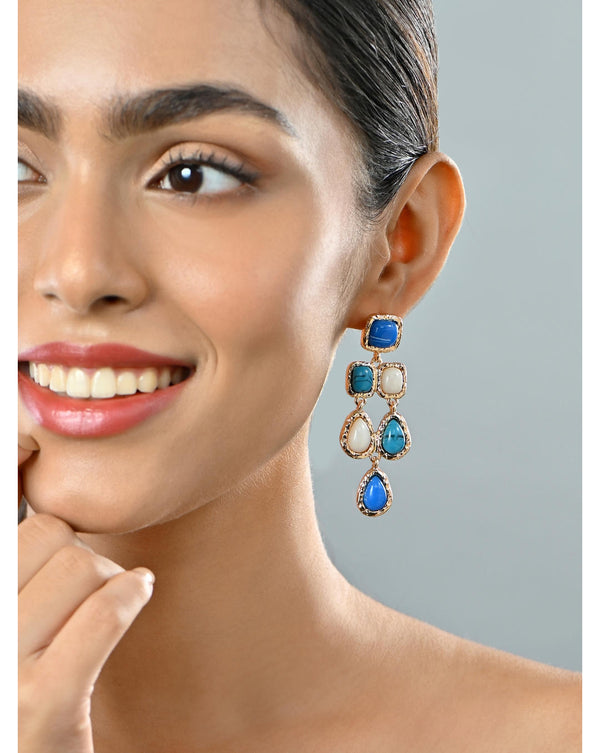 A woman wearing gold-toned sapphire blue and white enamelled partywear drop earrings.