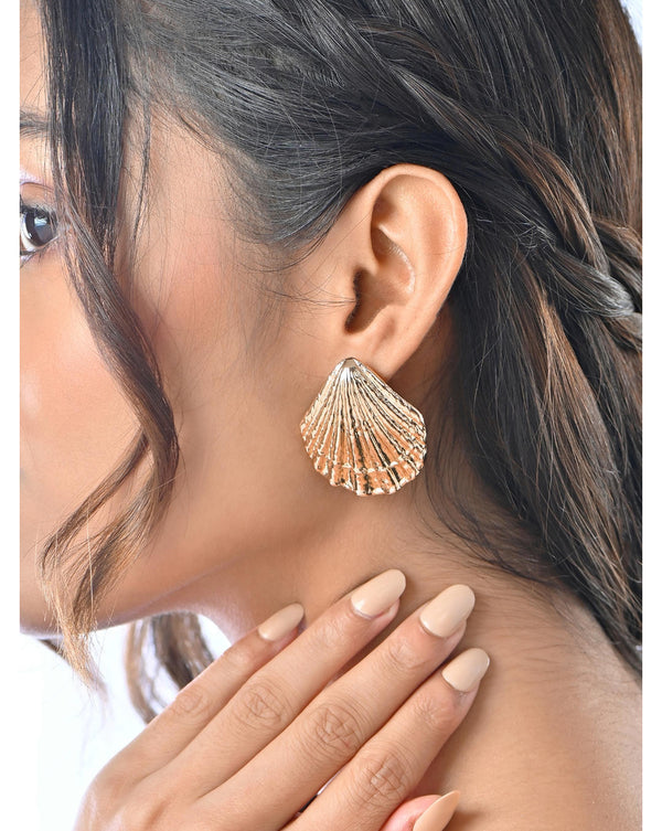A person wearing gold-plated alloy stud earrings shaped like a seashell with a glossy finish.